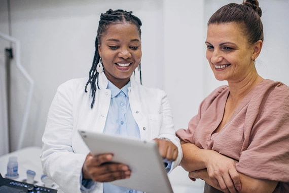 A doctor and patient discussing medical results on a tablet