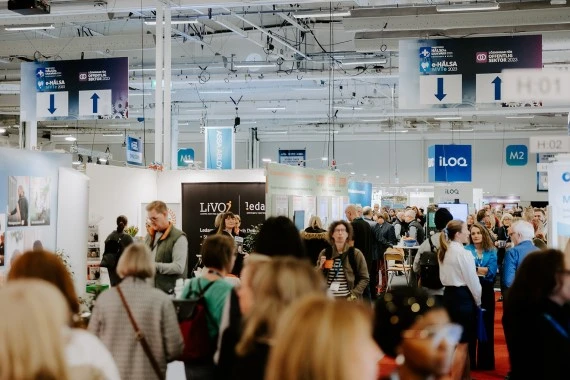 Personer som rör sig i en stor mässhall. Foto.