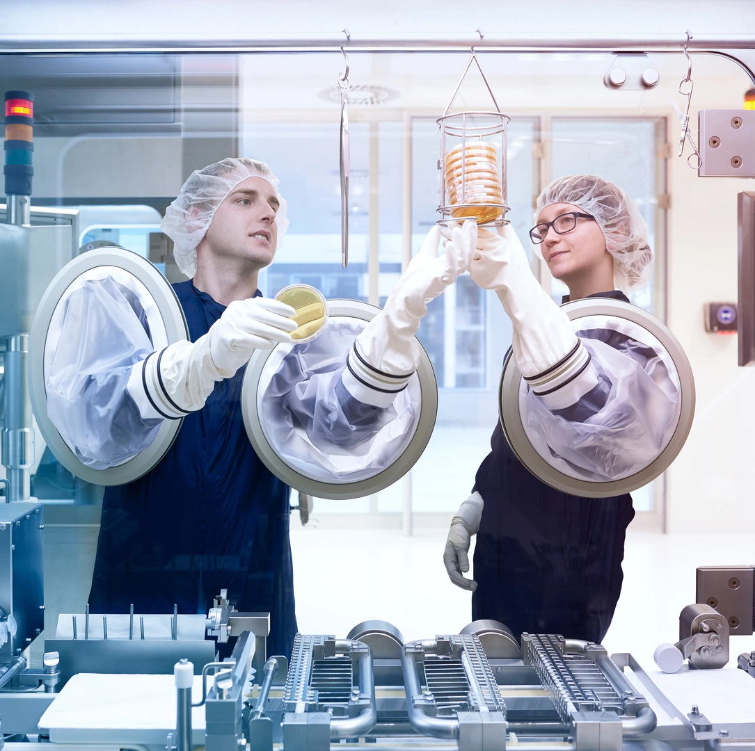 Two production specialists work on a machine