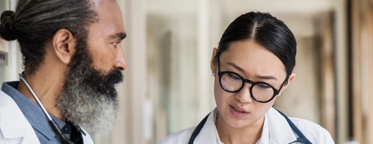 Zwei Ärzt*innen lesen in einer Akte